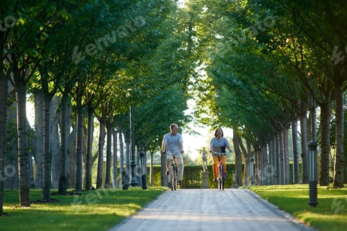 Preview: Happy mature couple ride bikes outdoors.