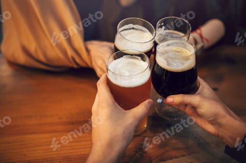 Preview: hands of people holding beer and cheering in brewery pub