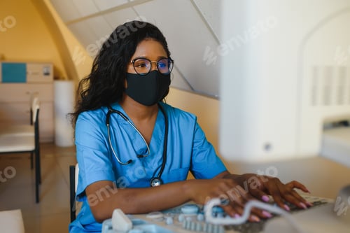 Preview: Young female African-american doctor working on modern ultrasound equipment.
