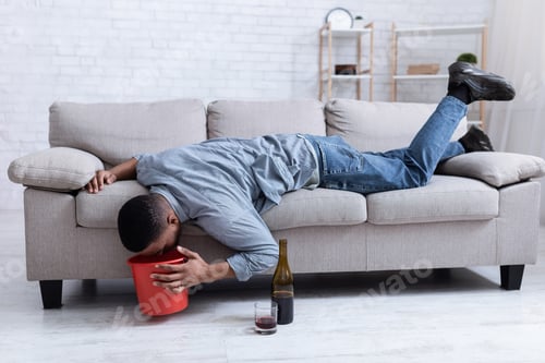 Preview: Drunk Man Vomiting Into Bucket After Drinking Wine Lying Indoor