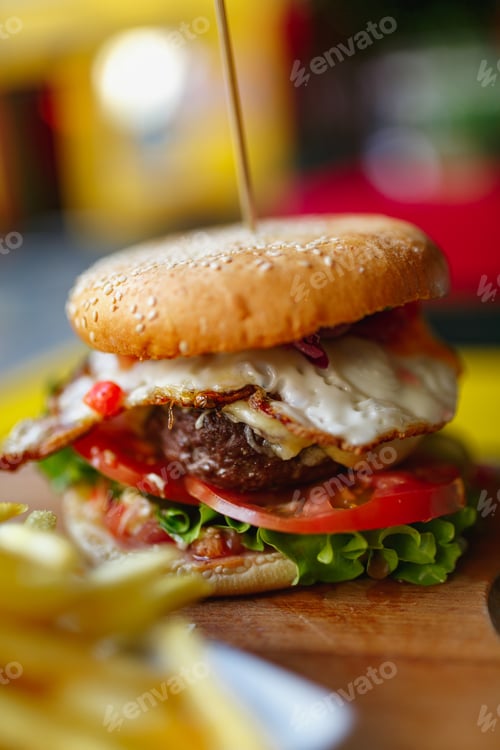 Preview: Vertical closeup shot of fresh tasty burger and french fries on a wooden table