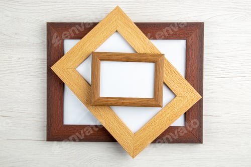 Preview: Overhead view of stacked small and big empty picture frames on white wooden background