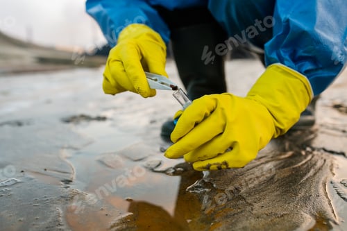 Preview: Contemporary ecologist in rubber gloves and protective blue coveralls taking sample of toxic soil