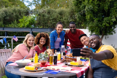 Preview: Happy diverse group of friends taking selfie and having dinner at balcony with flags of usa