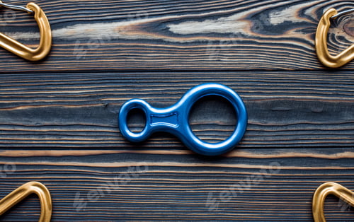 Preview: Isolated photo of climbing equipment. Parts of carabiners lying on the wooden table