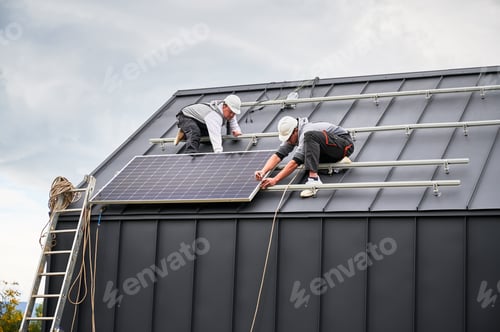 Preview: Technicians installing photovoltaic solar panels on roof of house.