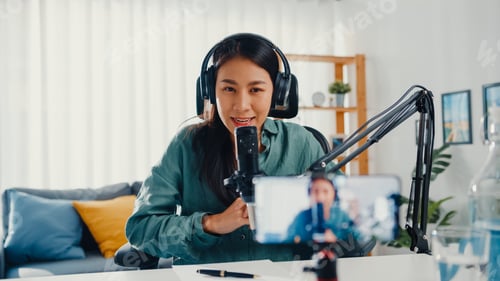 Preview: Asia girl use microphone wear headphone record content with smart phone for online audience listen.