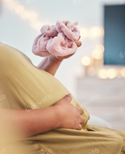 Preview: Baby shoes, pregnant stomach and woman hands with baby clothes holding her abdomen. Mother, mom lov