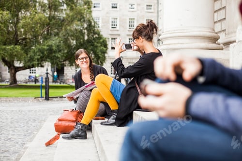 Preview: Woman photographing friend while sitting on steps