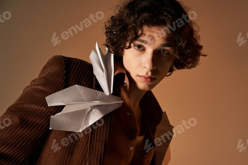 Preview: Young man showcases unique style with paper planes in a cozy studio setting