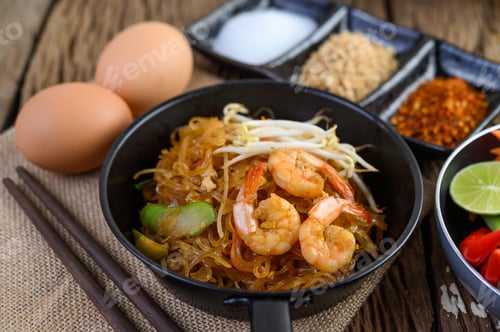 Preview: Padthai shrimp in a black bowl with eggs and Seasoning on wooden table.