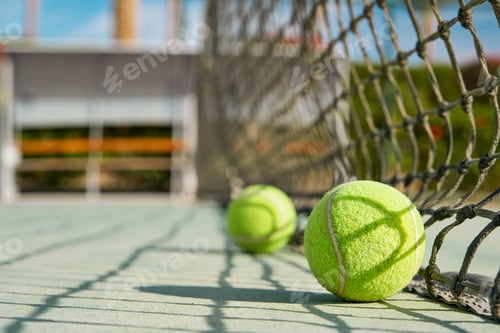 Preview: Tennis ball. Green tennis ball lies near net on tennis court on sunny day. Concept of healthy life