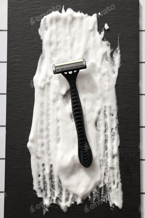 Preview: Shaving foam and disposable men's razor on black background, top view