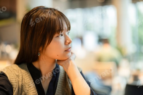 Preview: Young woman thinking and pondering in london cafe