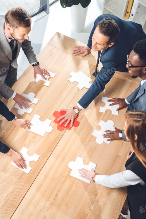 Preview: high angle view of businesspeople assembling puzzle on conference table