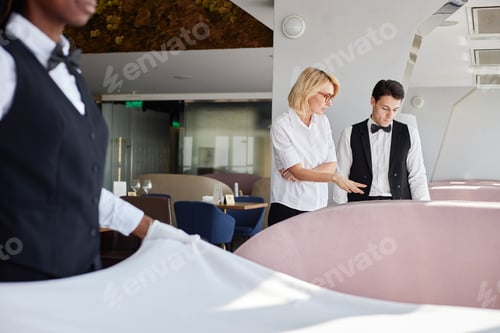 Preview: Caucasian Middle Aged Woman Supervising Young Adult Man Setting Table