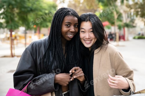 Preview: Portrait of two beautiful young women looking at camera and holding shopping bags. Smiling