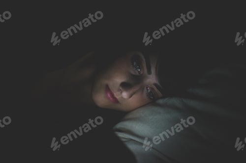 Preview: young woman using smart phone in bed at night