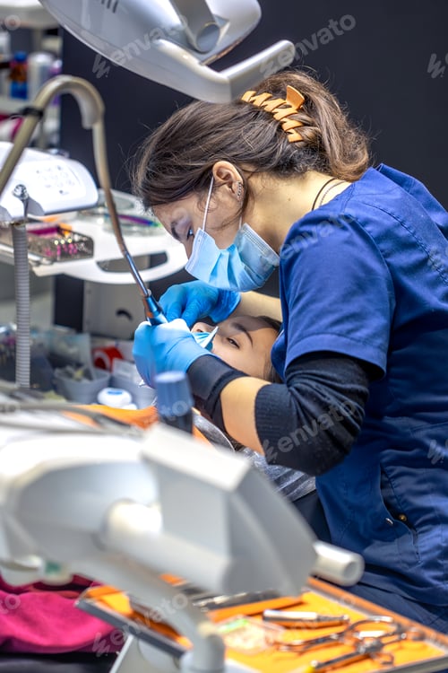 Preview: Young female dentist in dental office. Dentist at work. Dental treatment concept.