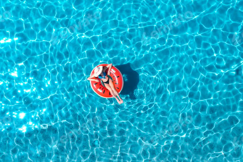Preview: Aerial view of a young woman swimming with red swim ring