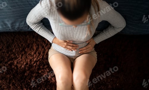Preview: Adult Woman with Stomach Discomfort Sitting at Home