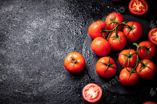 Preview: Halves and whole tomatoes on a branch on a stone board.