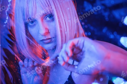 Preview: Posing for camera. Stylish woman with white hair is behind wet transparent plastic sheet