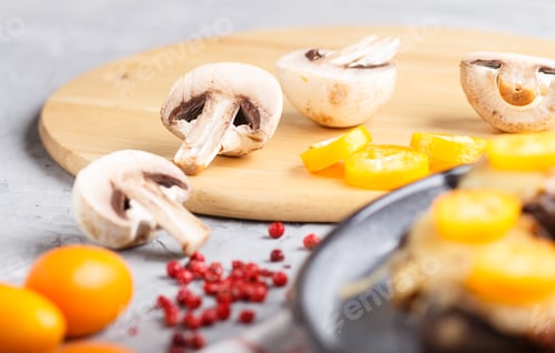 Preview: sliced raw champignons with kumquats on a gray concrete background. side view, close up, macro.