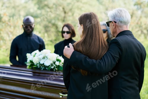 Preview: Back view of mature man in black suit embracing his grieving daughter