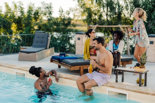 Preview: Friends enjoying drinks and conversation by the pool during summer vacation