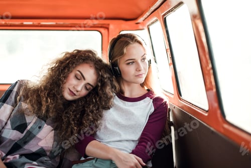 Preview: Young female friends on a roadtrip through countryside, sitting in minivan.