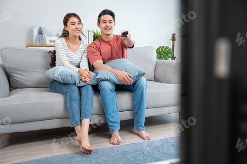 Preview: Asian young loving couple watch movie together in living room at home.