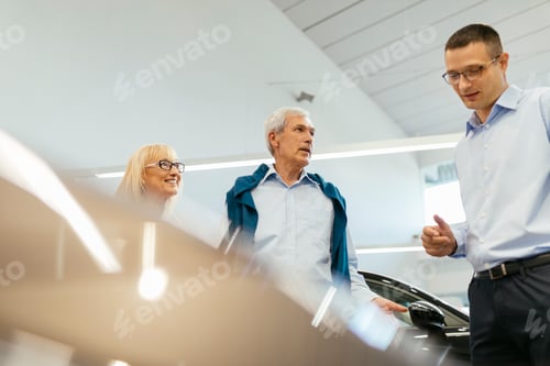 Preview: Senior couple couple talking with salesperson in car dealership