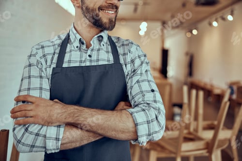 Preview: Joyful bearded man in apron keeping arms crossed