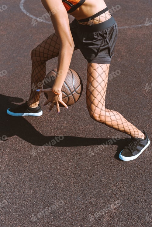 Preview: Cropped shot of young woman dribbling a basketball ball at sports court