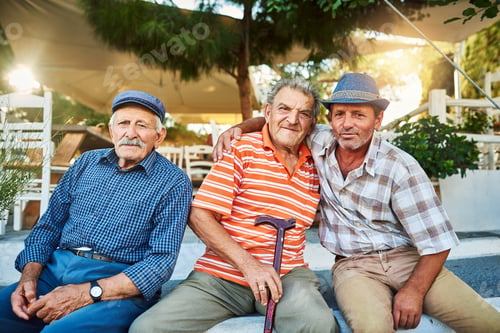 Preview: Portrait of a group of cheerful senior men sitting together while looking into the camera outside