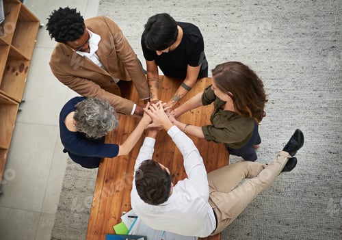 Preview: High angle shot of a group of unrecognizable businesspeople putting their hands in a huddle