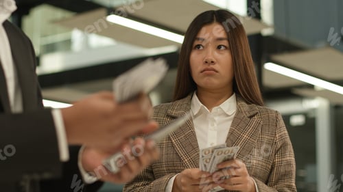 Preview: Sad offended upset Asian woman Korean businesswoman hold little money look at businessman colleague