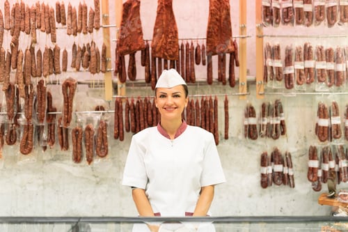 Smiling Woman with Meats in a Market