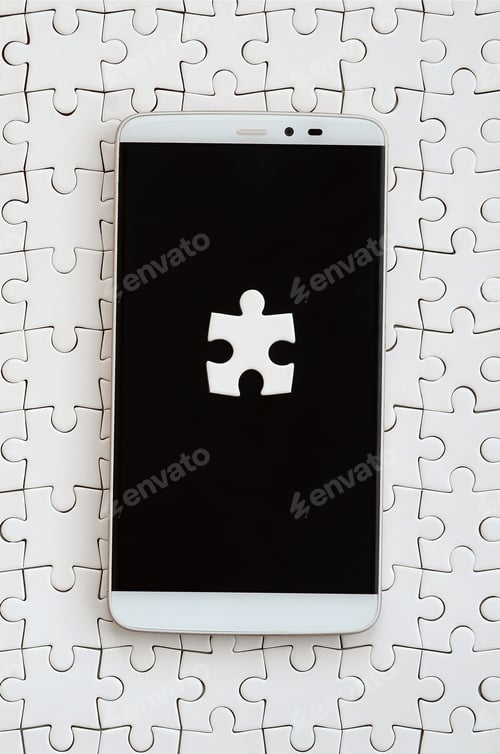 Preview: A modern big smartphone with several puzzle elements on the touch screen lies on a white