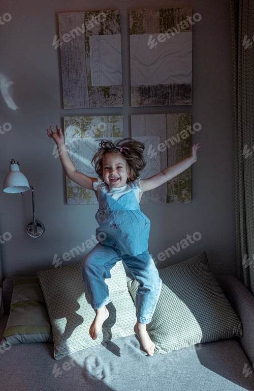 Preview: Kids being kids. A little girl jumping on the bed with joy