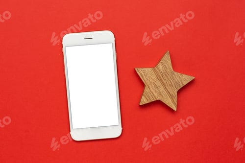 Preview: Mobile phone with wooden Christmas tree decoration on red color paper background