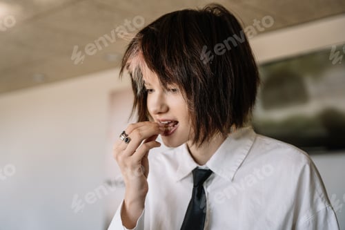 Preview: woman with short hair putting food in her mouth with her hand