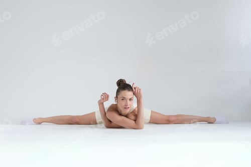 Preview: A flexible woman performs a full split while resting on the floor, maintaining a calm and confident