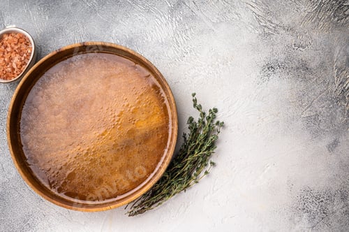 Preview: Chicken Bouillon or Broth in a wooden plate. white background. top view