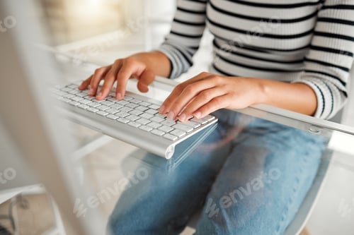 Preview: Businessperson typing on a keyboard working on a desktop computer while sitting at a desk at work.