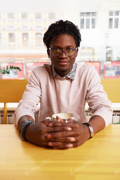 Preview: African American teenager in glasses talking on a smartphone and drinking coffee. Portrait of an