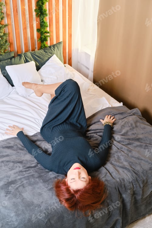 Preview: Fifty years old red haired woman lying upside down in bedroom