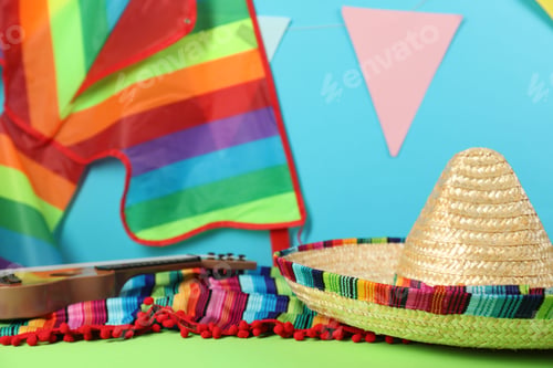 Vista previa: Mexican sombrero hat and poncho on green table, closeup. Space for text