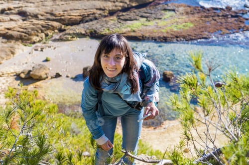 Preview: young woman wearing casual clothes standing on the beach while looking to camera in a bright day